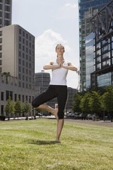 Germany, Berlin, Young woman exercising yoga, eyes closed - SKF00104