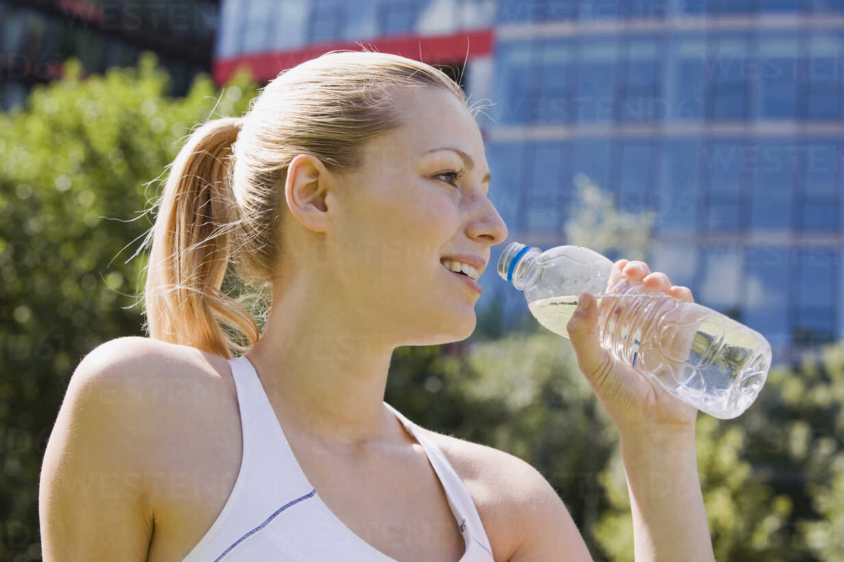 Teenage girl drinks water from bottle Stock Photo by