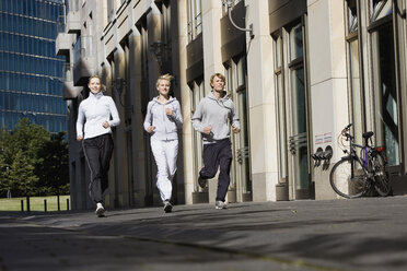 Deutschland, Berlin, Drei Freunde joggen zusammen - SKF00070