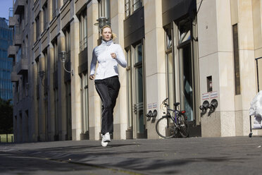 Deutschland, Berlin, Junge Frau joggt in der Stadt - SKF00066