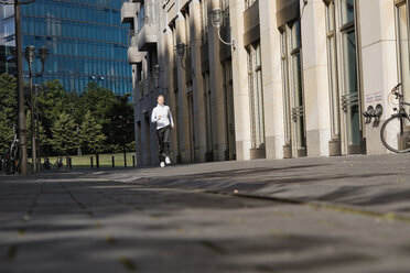 Deutschland, Berlin, Junge Frau joggt in der Stadt - SKF00065