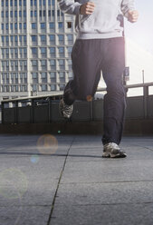 Deutschland, Berlin, Person beim Joggen auf der Straße, Wolkenkratzer im Hintergrund, niedriger Ausschnitt - SKF00055
