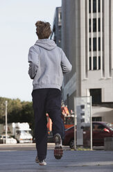 Germany, Berlin, Young man jogging, skyscrapers in background - SKF00053