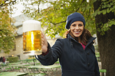 Deutschland, Bayern, München, Englischer Garten, Frau im Biergarten hält Bierkrug, lächelnd, Porträt - WESTF14094