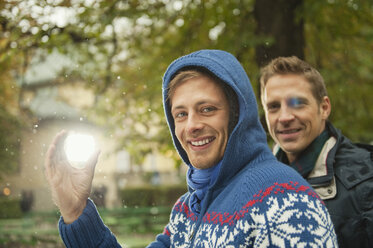 Deutschland, Bayern, München, Englischer Garten, Zwei Männer im Biergarten, einer von ihnen hält eine Lampe, lächelnd, Porträt, Nahaufnahme - WESTF14093