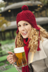 Deutschland, Bayern, Englischer Garten, Frau im Biergarten mit Bierkrug in der Hand, leckt sich die Lippen, Porträt - WESTF14091