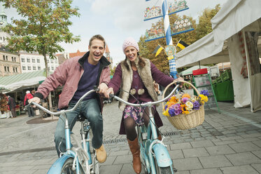 Germany, Bavaria, Munich, Viktualienmarkt, Couple with bicycles, laughing, portrait - WESTF14037