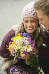 Germany, Bavaria, Munich, Couple, woman holding bunch of flowers, smiling, portrait - WESTF14030