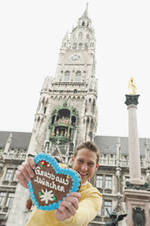 Germany, Bavaria, Munich, Marienplatz, Man holding gingerbread heart, smiling, portrait - WESTF14015