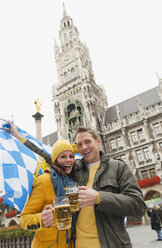 Deutschland, Bayern, München, Marienplatz, Paar mit Bierkrügen und bayerischer Flagge, lachend, Porträt - WESTF14010