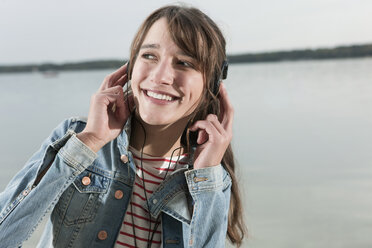 Germany, Berlin, Lake Wannsee, Woman wearing headphones, smiling, portrait, close-up - WESTF13982