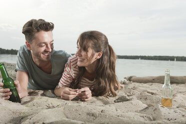 Germany, Berlin, Lake Wannsee, Young couple lying on beach, smiling, portrait - WESTF13965