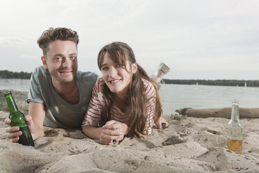 Germany, Berlin, Lake Wannsee, Young couple lying on beach, smiling, portrait - WESTF13964