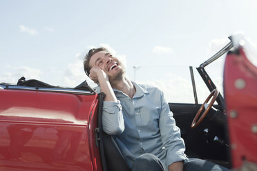 Deutschland, Berlin, Junger Mann im Cabrio sitzend, Mobiltelefon benutzend, Portrait - WESTF13939