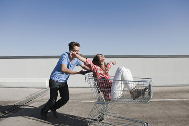 Germany, Berlin, Young man pushing young woman in shopping cart - WESTF13936