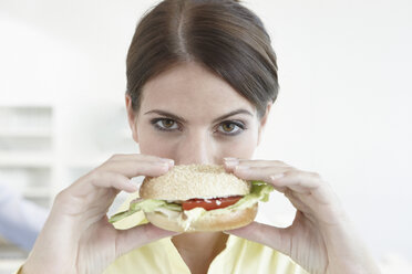 Germany, Cologne, Businesswoman holding sandwich, portrait, close-up - JOF00081