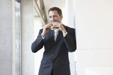 Germany, Cologne, Businessman eating sandwich, portrait - JOF00066
