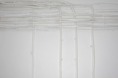 Rohre und Elektrokabel auf weißer Wand - TLF00382
