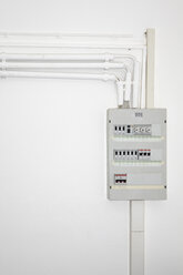 Rohre, Elektrokabel und Sicherungskasten auf weißer Wand - TLF00379