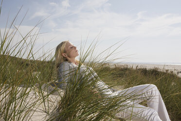 Germany, Schleswig Holstein, Amrum, Woman relaxing in dunes, eyes closed - RBF00173