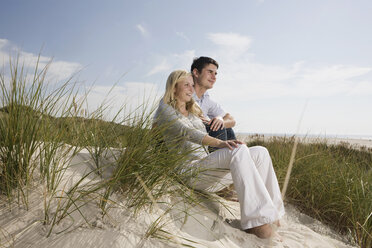 Germany, Schleswig Holstein, Amrum, Couple sitting in sand dunes - RBF00161