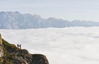 Österreich, Steiermark, Reiteralm, Wandererpaar bewundert Aussicht über Wolken - HHF03138