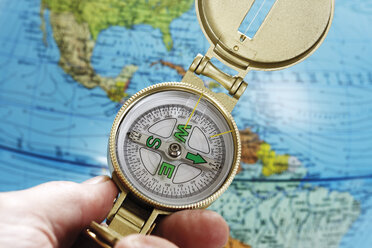 Person hält Kompass, Globus im Hintergrund, Nahaufnahme - 12001CS-U