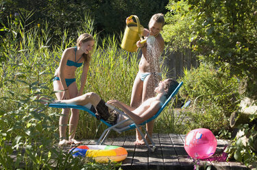 Österreich, Salzburger Land, Teenager-Mädchen (14-15) gießt Wasser über Teenager-Junge (14-15) - WWF01130