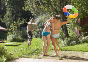 Austria, Salzburger Land, Teenagers (14-15) in garden having fun with hosepipe - WWF01126