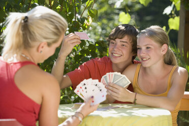 Austria, Salzburger Land, Teenagers (14-15) playing cards in garden - WWF01118