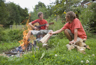 Austria, Salzburger Land, Teenage boys (14-15) in garden, sitting at campfire - WWF01113