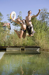 Austria, Salzburger Land, Teenagers (14-15) jumping into lake - WWF01111