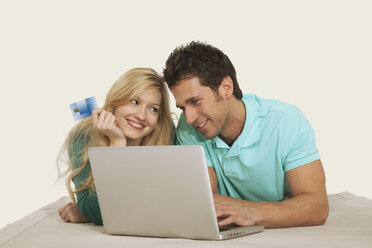 Couple lying and using laptop, smiling - WESTF14592