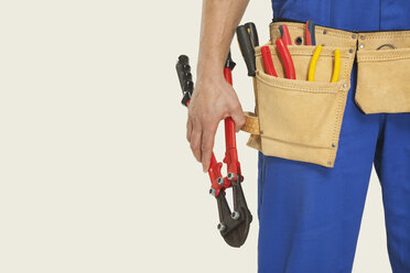 Man wearing tool belt holding pliers, mid section, close-up - WESTF14500