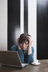 Frau sitzend mit Laptop und Kaffeetasse - WESTF14405