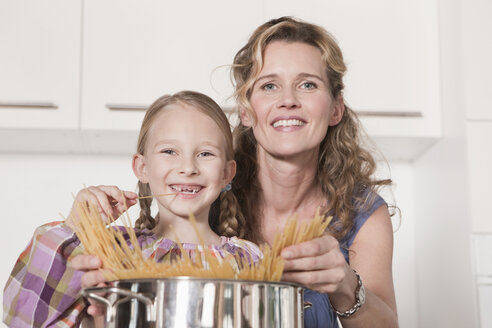 Deutschland, Köln, Mutter und Tochter (6-7) kochen Nudeln, lächelnd, Porträt - WESTF14346