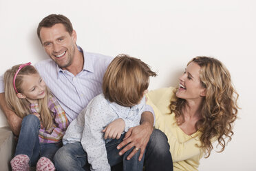 Germany, Cologne, Family sitting on steps of staircase, laughing, portrait, close-up - WESTF14337