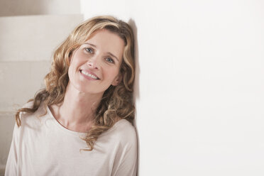 Germany, Cologne, Woman leaning against wall, smiling, portrait, close-up - WESTF14299