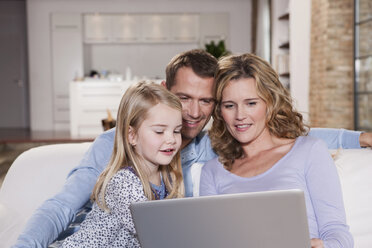 Germany, Cologne, Family on sofa using laptop, portrait - WESTF14250