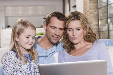 Germany, Cologne, Family on sofa using laptop, portrait - WESTF14249