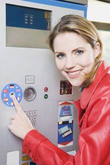 Deutschland, Bayern, München, Junge Frau am Fahrkartenautomat in der U-Bahn-Station, lächelnd, Porträt, Nahaufnahme - WESTF14217