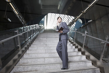 Germany, Bavaria, Munich, Business woman using mobile phone at subway station, standing on staircase - WESTF14131