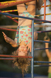 Germany, Baden Württemberg, Girl (4-5) hanging upside down from junglegym, laughing, portrait - SHF00441