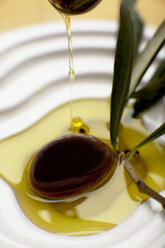 Olive oil poured over olive, elevated view, close-up - SCF00373