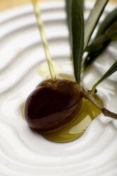 Olive oil poured over olive, elevated view, close-up - SCF00372