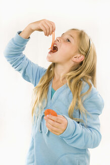 Girl (8-9) eating wine gum, smiling, portrait - RNF00238