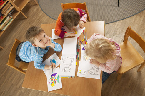 Deutschland, Kinder im Kinderzimmer sitzen am Tisch und malen Bilder, Blick von oben - RNF00222