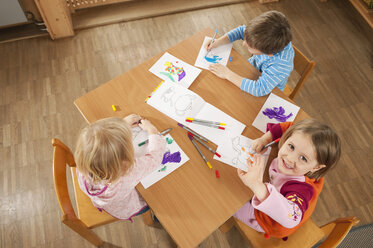 Deutschland, Kinder im Kinderzimmer sitzen am Tisch und malen Bilder, Blick von oben - RNF00221