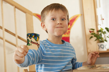 Deutschland, Junge (4-5) im Kinderzimmer mit Puzzleteil, Porträt - RNF00217