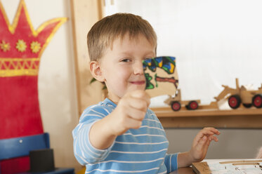 Deutschland, Junge (4-5) im Kinderzimmer mit Puzzleteil, Porträt - RNF00216